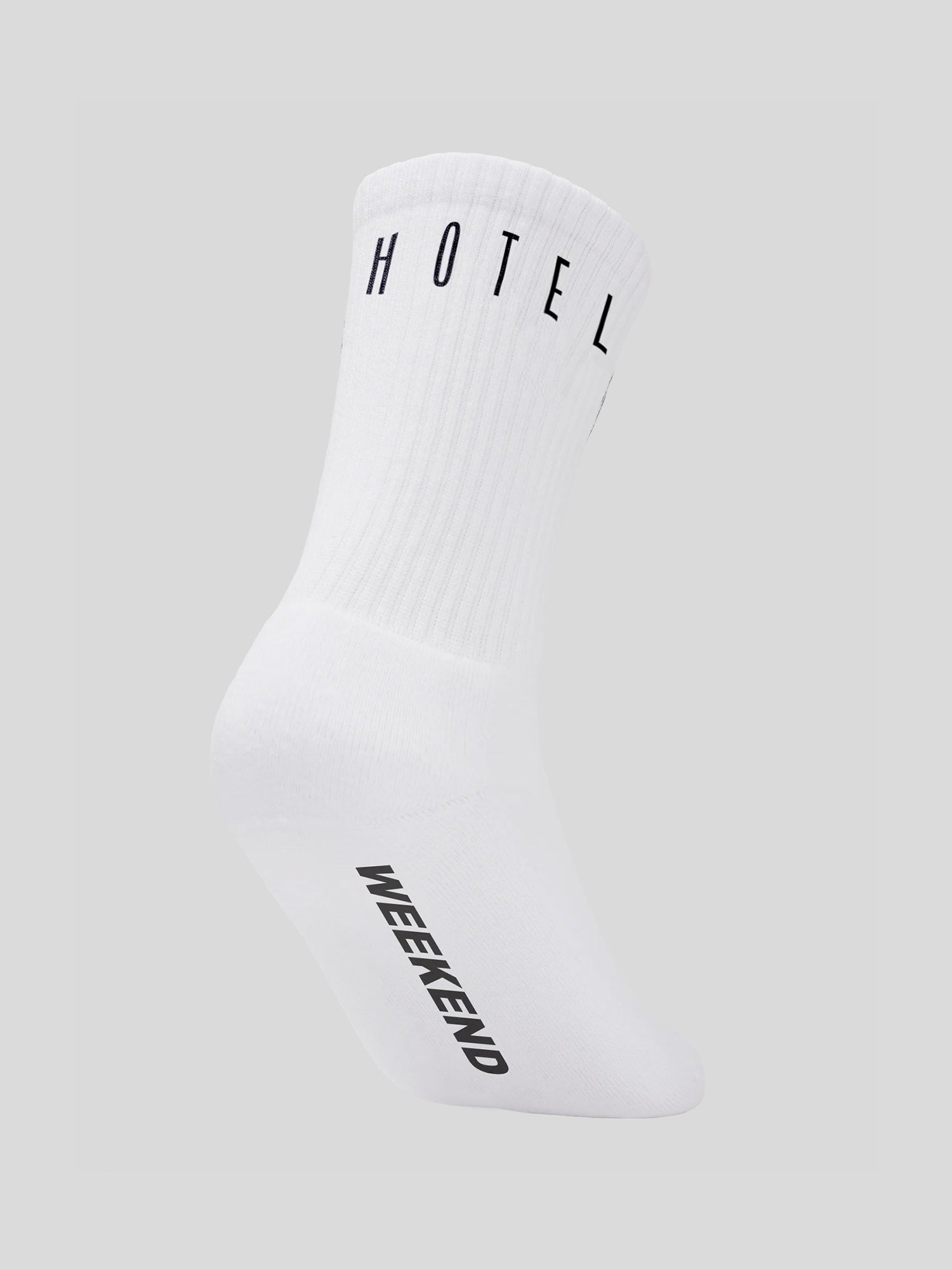 Weiße Socke mit schwarzem „HOTEL“-Schriftzug am Bündchen und großem „WEEKEND“-Print auf der Sohle – beide in klarer Großbuchstabentypografie.
