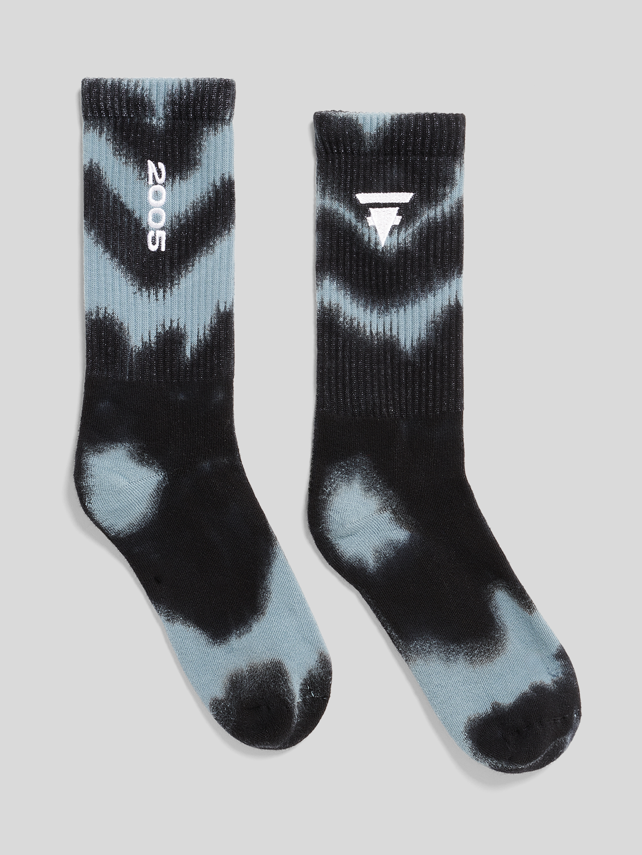 Paar schwarze und hellblaue Batik-Socken. Linke Socke mit weißem Kreislogo am Schaft, rechte Socke mit weißer Zahl ‚2025