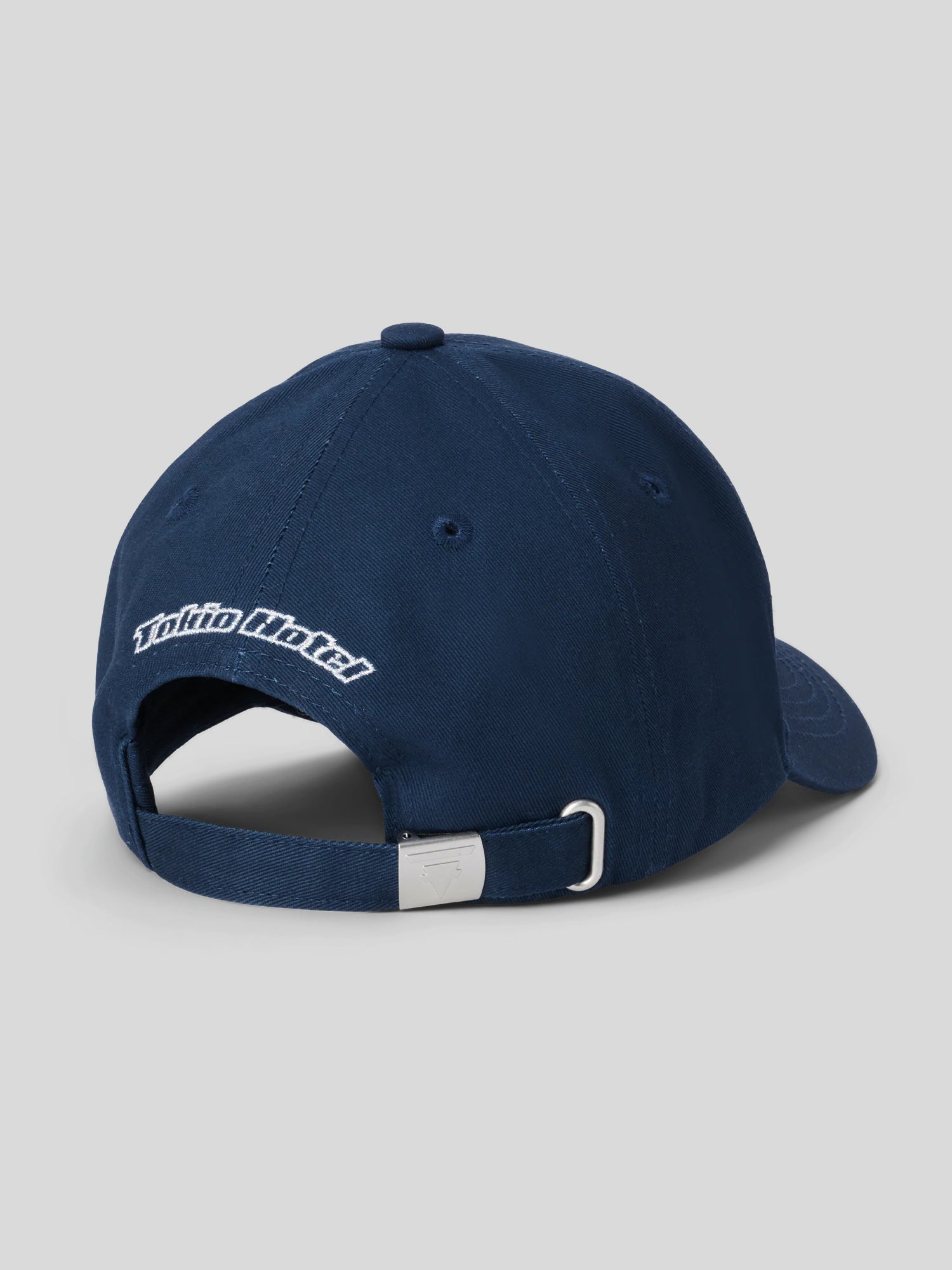 Rückansicht der dunkelblauen Cap mit weißem „Tokio Hotel“-Schriftzug über dem verstellbaren Metallverschluss mit Schnalle.