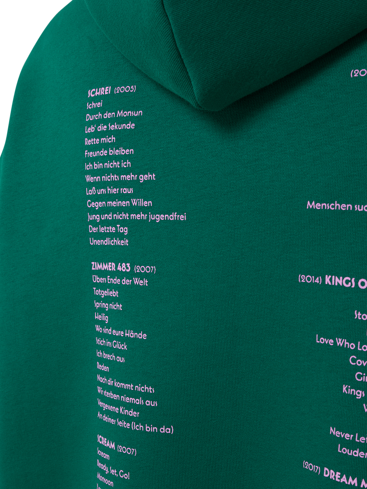 Nahaufnahme der Songliste auf dem Rücken des Hoodies, sichtbar sind die Tracklists zu den Alben „Schrei“, „Zimmer 483“ und „Scream“ in rosa Schrift auf grünem Stoff.Nahaufnahme der Songliste auf dem Rücken des Hoodies, sichtbar sind die Tracklists zu den Alben „Schrei“, „Zimmer 483“ und „Scream“ in rosa Schrift auf grünem Stoff.
