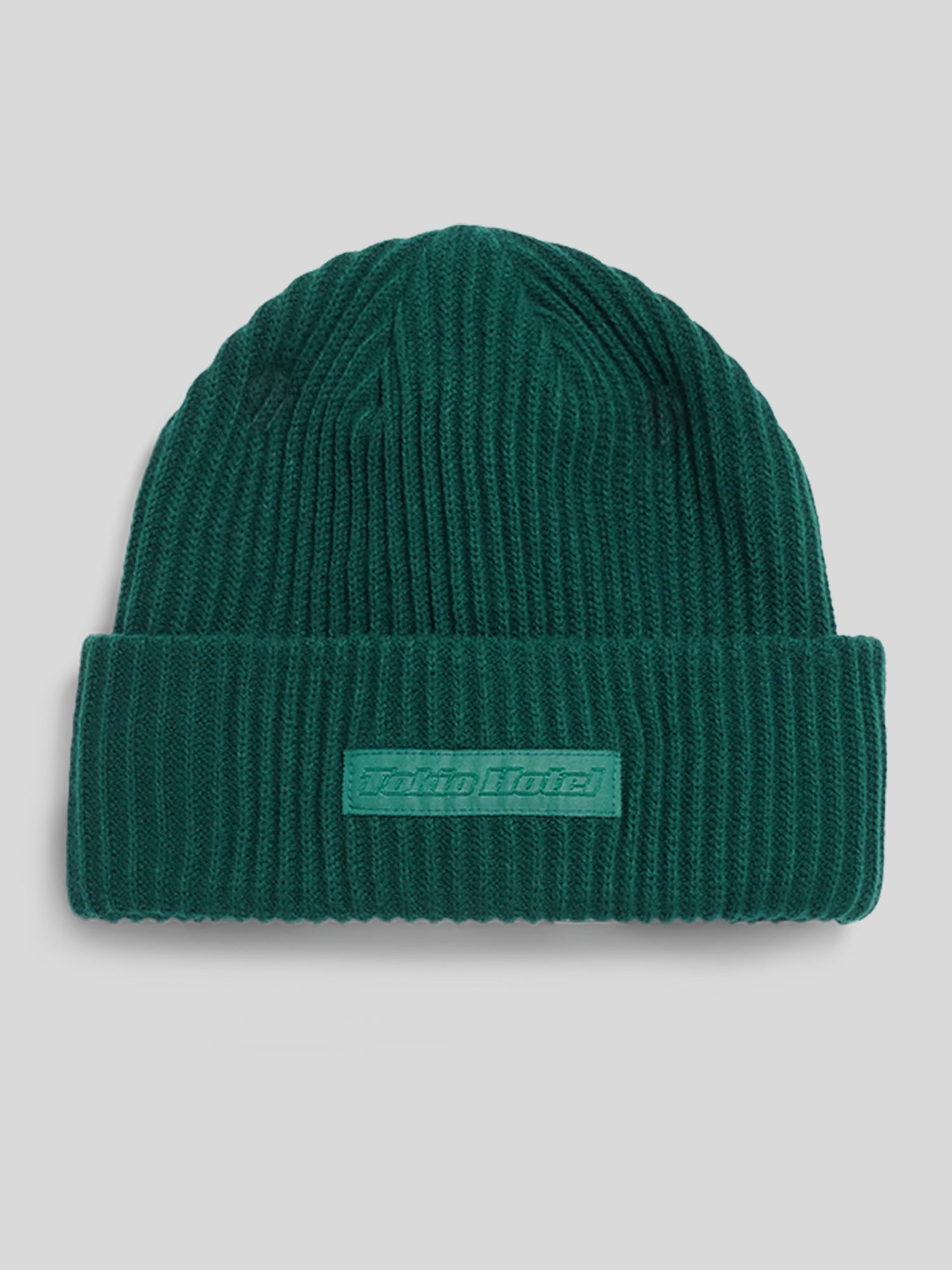 Dunkelgrüne, gerippte Beanie-Mütze mit breitem Umschlag. Auf dem Umschlag befindet sich ein gewebtes Stoffpatch in passender Farbe mit erhabenem „Tokio Hotel“-Schriftzug.