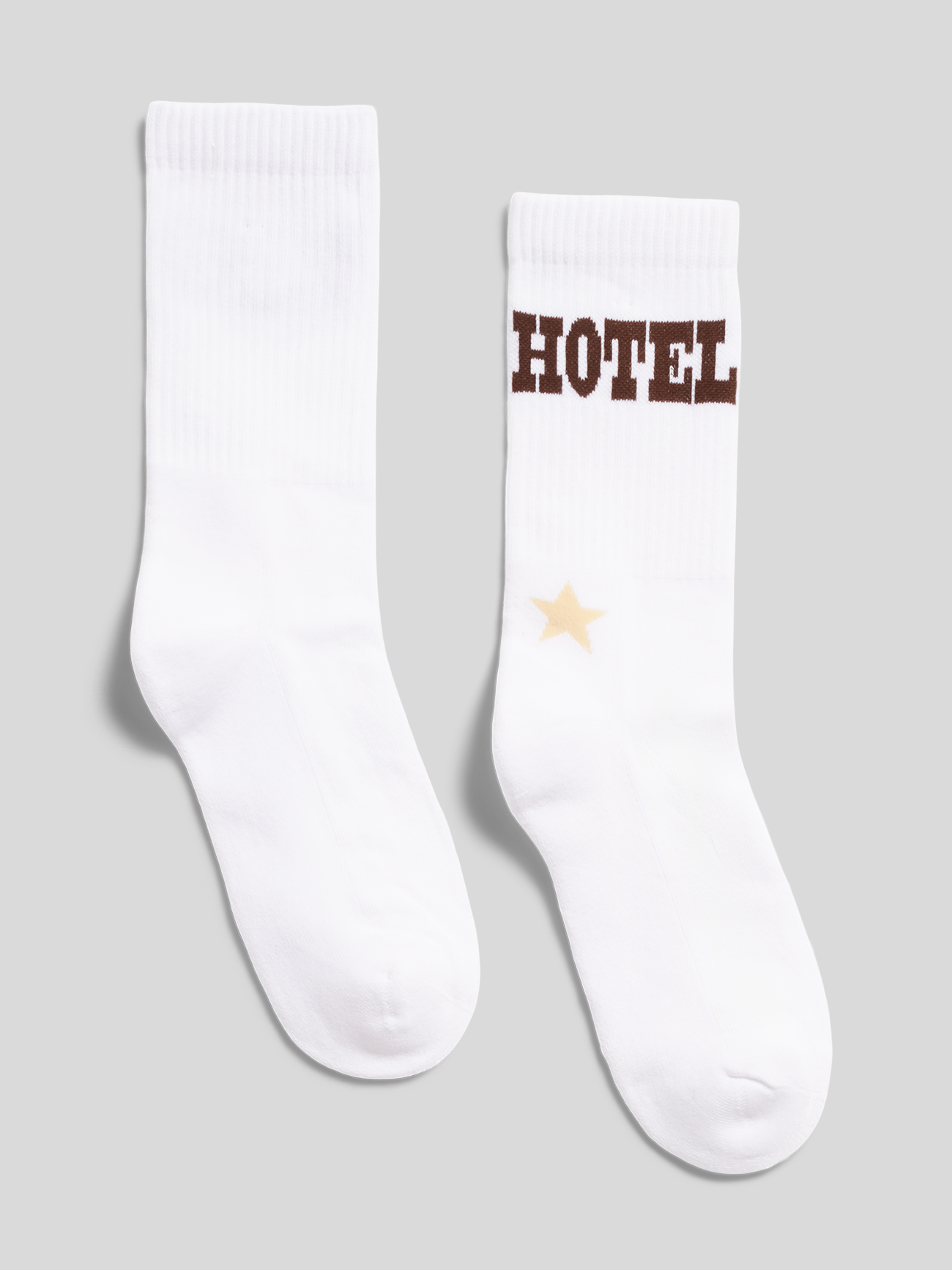 Weiße Tokio-Hotel-Socken mit braunem „HOTEL“-Schriftzug und Sternmotiv, von hinten fotografiert.