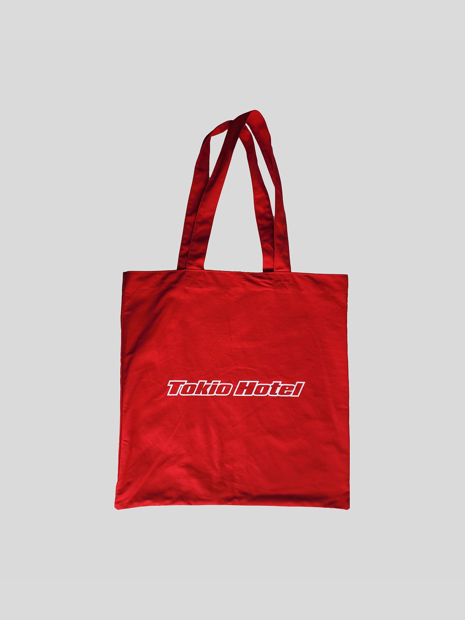Rote Stofftragetasche mit langen Henkeln und weißem „Tokio Hotel“-Schriftzug in dynamischer Blockschrift auf der Front.