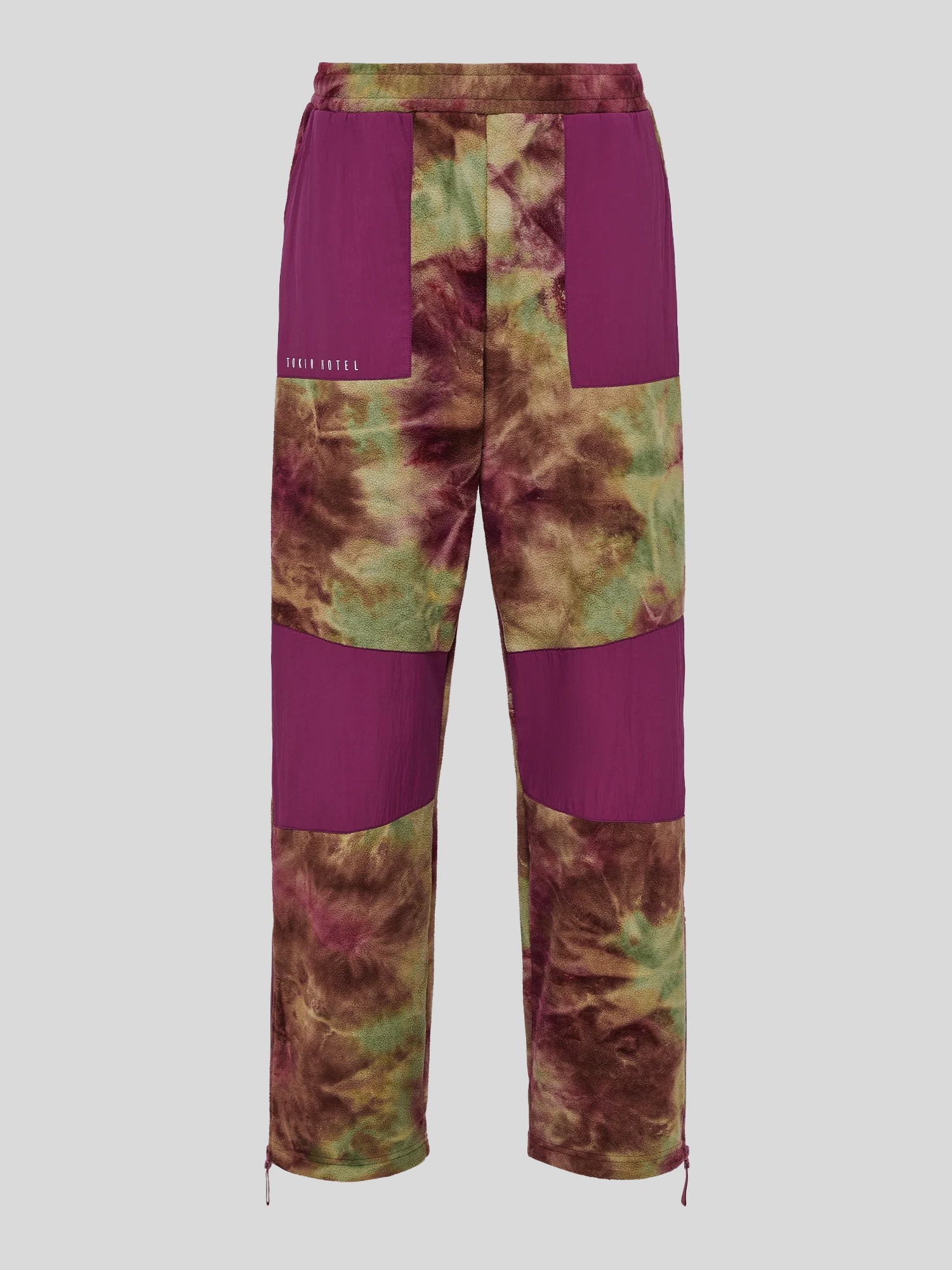 Fleecehose mit Batikmuster in Grün-Bordeaux und großflächigen, violetten Einsätzen im Oberschenkel- und Kniebereich. Elastischer Bund und weißer „TOKIO HOTEL“-Print vorn links.