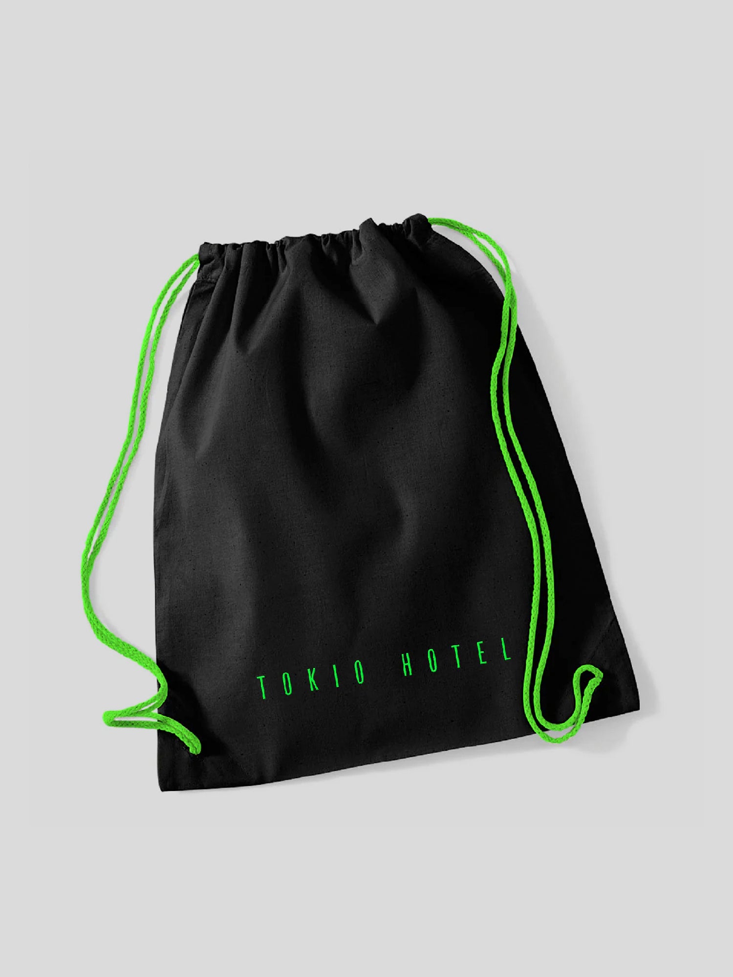 Schwarzer Turnbeutel mit neon-grünen Kordeln, die als Träger und Verschluss dienen. Am unteren Rand der Vorderseite ist in grüner, schmaler Großschrift der Schriftzug „TOKIO HOTEL“ aufgedruckt.