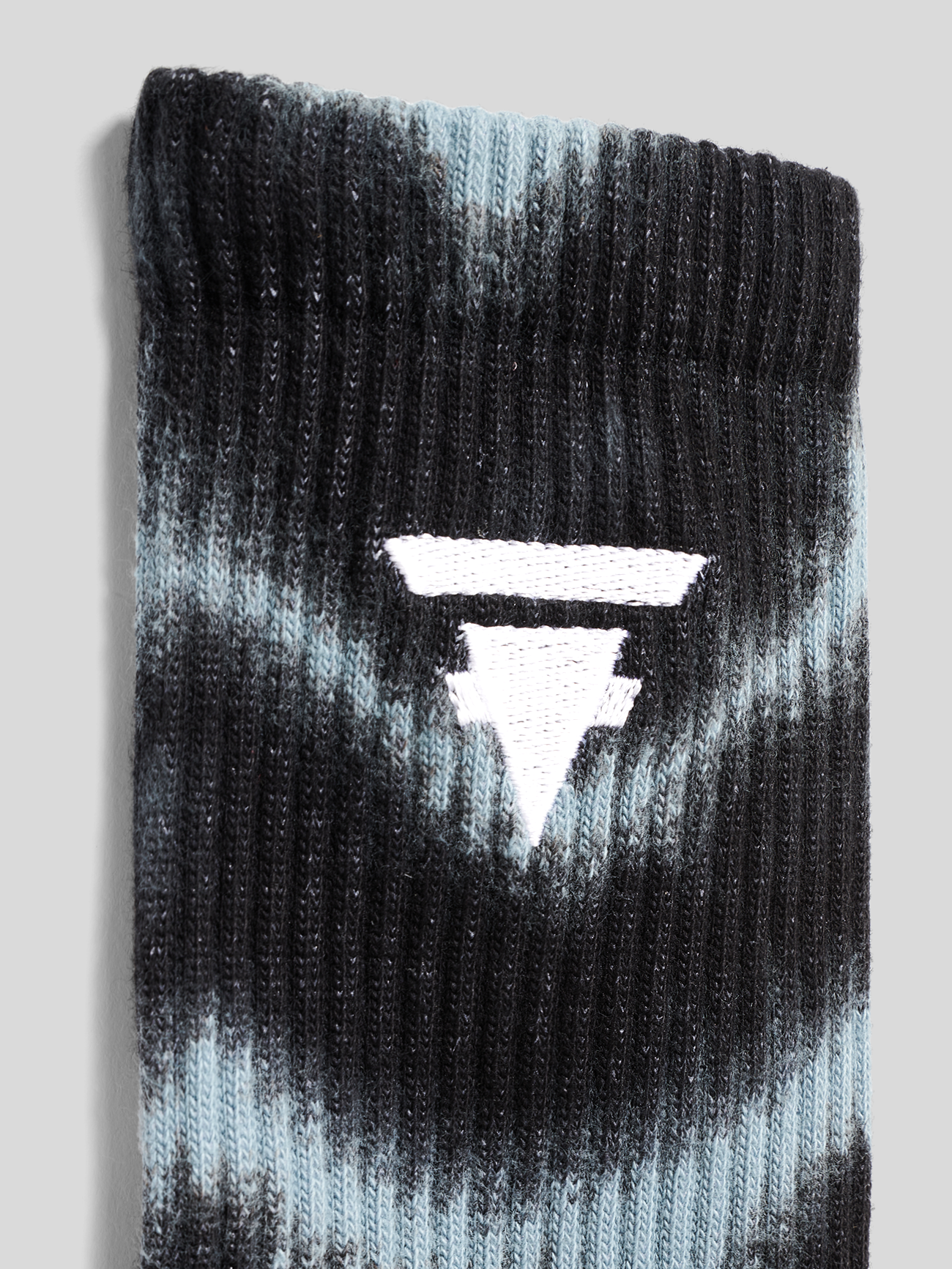 Paar schwarze und hellblaue Batik-Socken. Linke Socke mit TokioHotel am Schaft