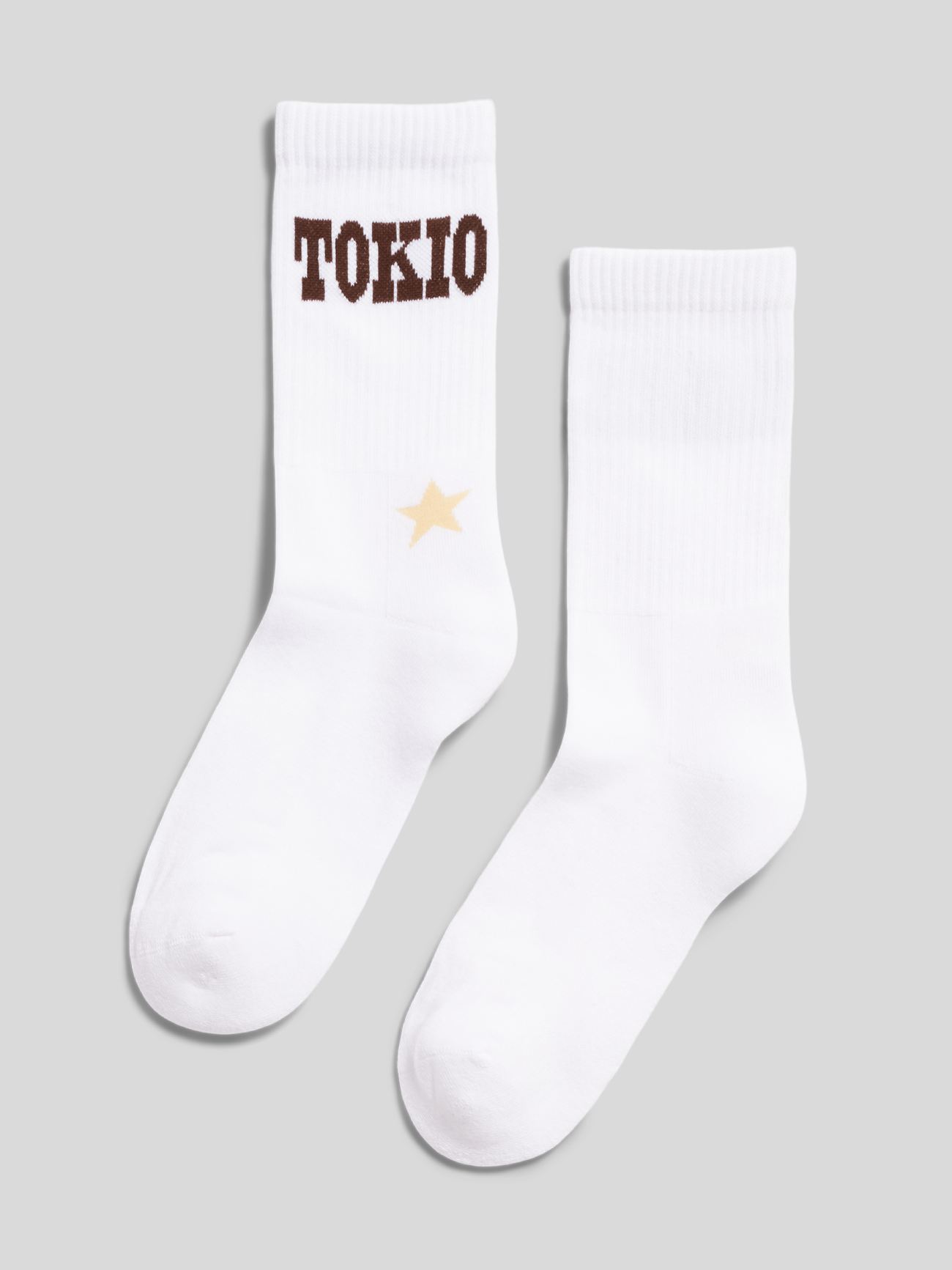 Weiße Tokio-Hotel-Socken mit braunem „TOKIO“-Schriftzug und kleinem Sternmotiv.
